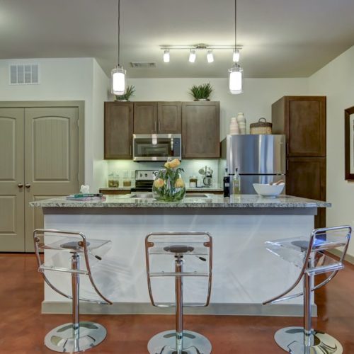Model apartment kitchen with island and steel appliances