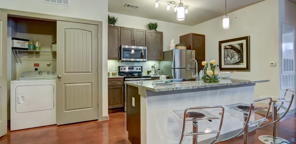 Model apartment kitchen with island and in-unit washer and dryer