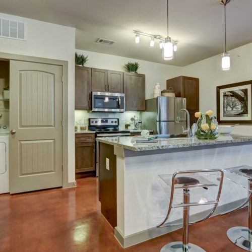 Model apartment kitchen with island and in-unit washer and dryer