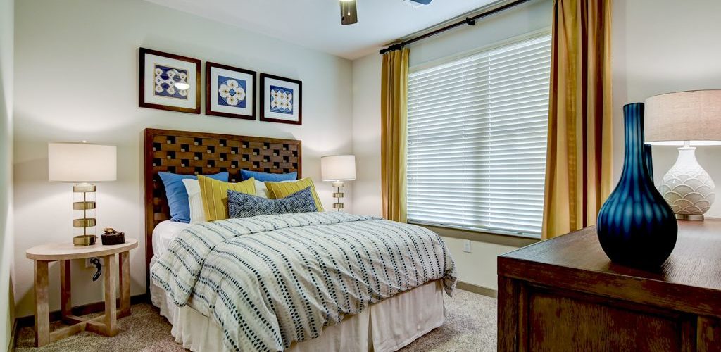 Model apartment carpeted and furnished bedroom with ceiling fan