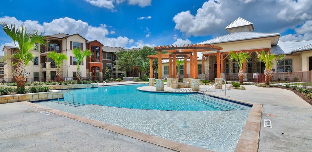 Side view of community pool and outdoor patio with fire pit