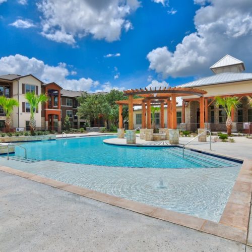 Side view of community pool and outdoor patio with fire pit